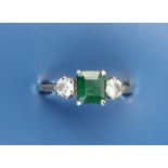 A small emerald & diamond set three stone ring, the emerald cut emerald weighing approximately 0.