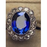 A sapphire & diamond cluster ring, the oval cut millegrain set sapphire weighing approximately 3