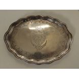 A small oval Neoclassical silver salver, having waved edge, engraved shield to centre on four ball