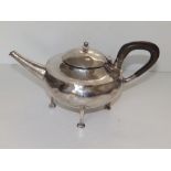 An Arts & Crafts circular silver teapot by A.E. Jones , having tapering spout and standing on four