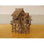 A small Oriental stoneware model of a house on stilts, 4.75" high - a/f.