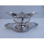 An Edwardian silver double-lipped sauce boat & stand, of plain design with gadrooned borders -