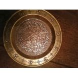 An Eastern silver inlaid brass tray, having a central star design within a border of script, 8"