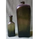 A large antique glass 'gin' bottle and one other smaller bottle. (2)