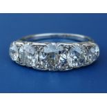 A graduated five stone old cut diamond ring in white metal, the central claw set stone weighing