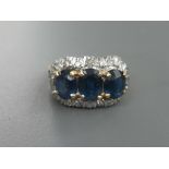 A three stone sapphire & diamond cluster style ring, the three claw set oval sapphires of total