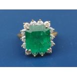 An emerald & diamond set rectangular cluster ring, the claw set emerald weighing approximately 6