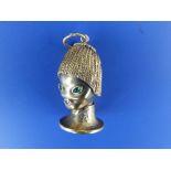 A stylised 14K Eastern head pendant with gem set eyes & mouth, 1.5" high.