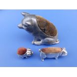 A pewter pin cushion in the form of a seated pig, 2.25" high and two small plated pin cushion