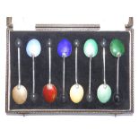 A cased set of eight bean-handled silver coffee spoons with guilloche enamel backs to bowls of