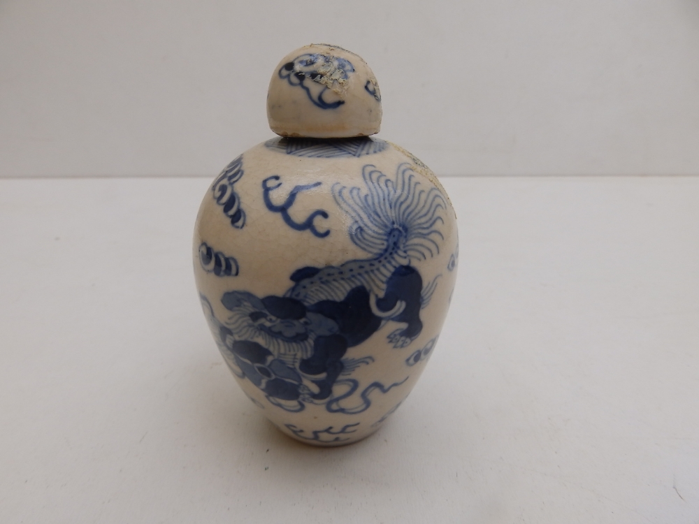 A small Chinese covered blue & white porcelain jar decorated with cavorting shishis amidst cloud