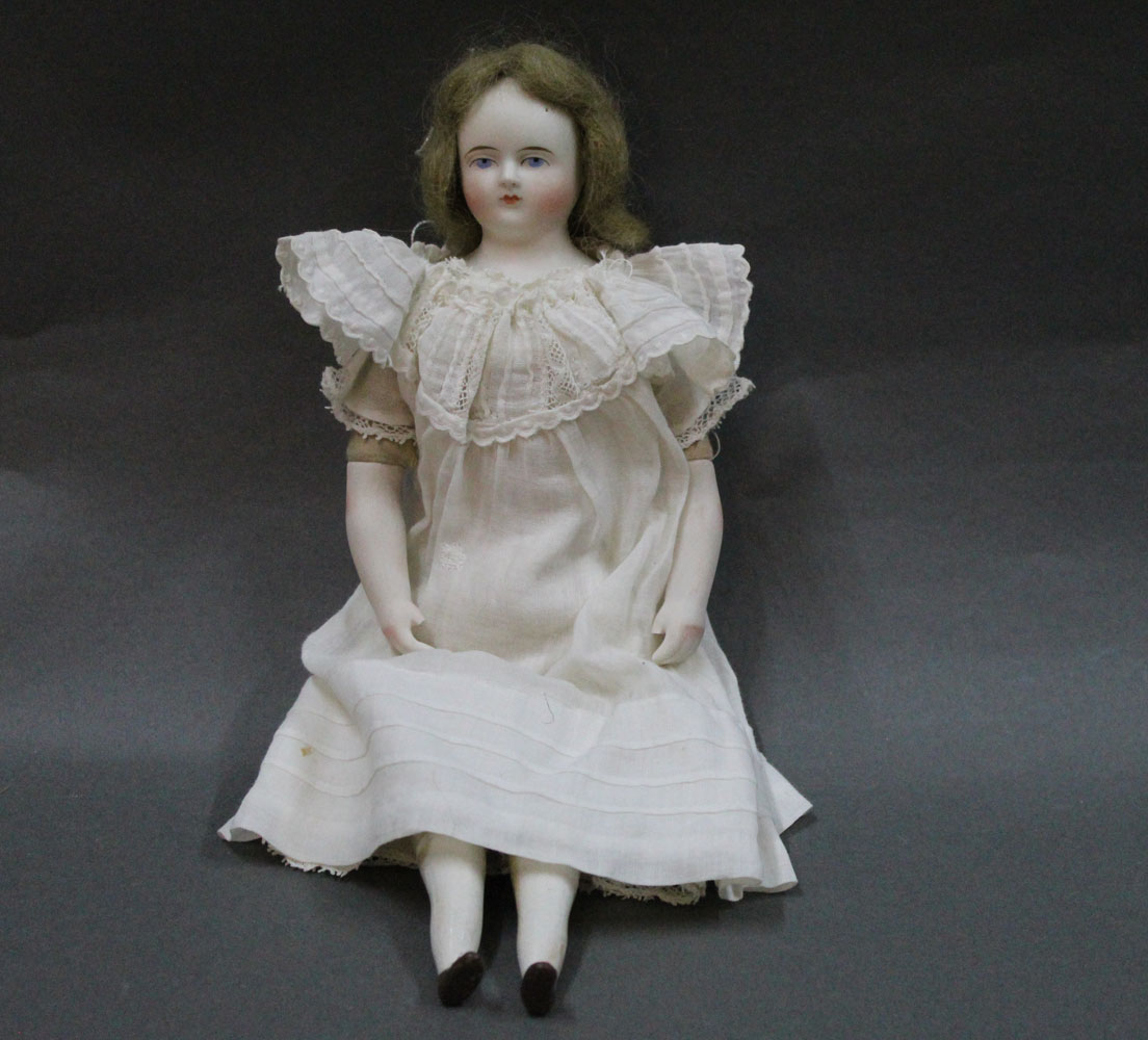 A mid 19th-century Parian bisque shoulder head doll, with wig, calico sawdust filled body,
