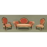 A Victorian walnut three piece salon suite, with oval backs and leaf carvings,