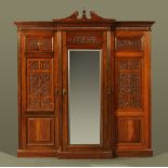 A Victorian walnut triple wardrobe, carved throughout with scrolled leafage motifs,