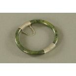A Chinese jade bangle with silver coloured metal mounts, external diameter 8 cm, internal 6.5 cm.