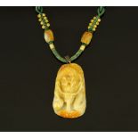 A carved jade pendant on silkwork and beaded necklace.