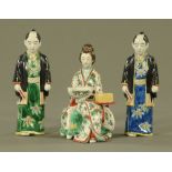 A Japanese porcelain figure of a seated lady, together with a pair of standing male figures.