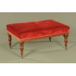A Victorian mahogany rectangular stool, upholstered in maroon material on turned legs and castors.