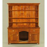 A reproduction oak dresser and rack, the upper section with moulded cornice over three shelves,
