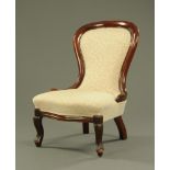 A Victorian mahogany nursing chair, upholstered in beige foliate patterned material.