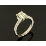 A platinum three stone diamond claw set ring, with central emerald cut diamond +/- 1.