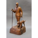 K Bateson, a carved wooden figure of huntsman with hound and thumbstick,