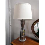 A ribbed metal table lamp with white coloured shade