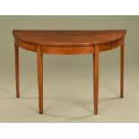 A George III mahogany demi lune side table, raised on tapered legs of square section.