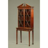 An Edwardian mahogany bookcase on stand, in the Adam style with triangular pediment,