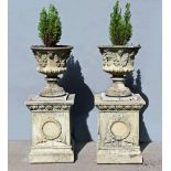 A large pair of composition garden urns, Campana shaped raised on large square plinths.