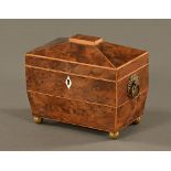 A George III burr yew tea caddy, of sarcophagus form with brass handles and ball feet,