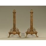 A pair of antique brass fire dogs, moulded with shells and mythical sea creatures.