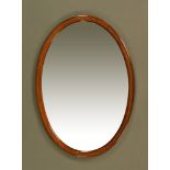 An Edwardian inlaid mahogany oval bevelled glass mirror. 86 cm x 61 cm.