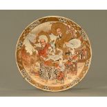 A Satsuma earthenware plate, decorated with figures and repeating line border. Diameter 32 cm.