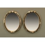 A pair of Irish ebony and gilt oval wall mirrors, with original plates. Each 68 cm x 53 cm.