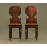 A pair of Regency oak hall chairs with silhouette backs. Height 93 cm, width across seat 36 cm.