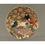 A large 19th century Japanese charger, depicting artists, scrolls and game playing.