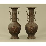 A pair of Japanese bronze vases, late 19th century relief moulded with birds and foliage.