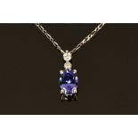 An 18 ct white gold pendant on chain, set with an oval cut tanzanite and diamonds.