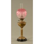 A Victorian brass oil lamp, with cranberry glass shade. Height including chimney 71 cm.