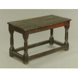 A 17th century oak table, with carved frieze, turned legs and low stretchers.