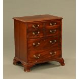 A George III mahogany cupboard, modelled as a chest of drawers with slides and cupboard space.