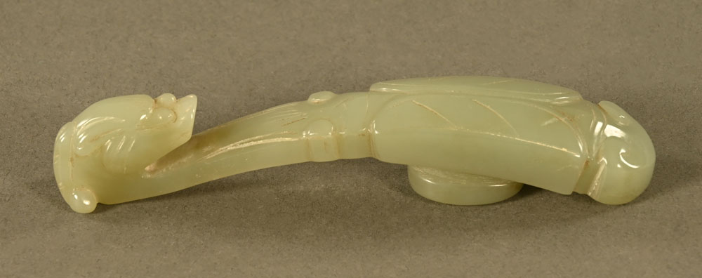 A Chinese carved jade button or belt hook in the form of a Chilong with folded wings. Length 11 cm.