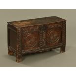 An antique oak coffer, with twin plank top and panelled carved front raised on stile feet.