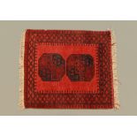 A small Eastern fringed rug, principal colours red and dark blue,