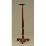 A 19th century bed post torchere, with circular top and triform base.