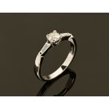 A platinum ring set with a diamond to centre and a baguette to each shoulder. Size M/N.