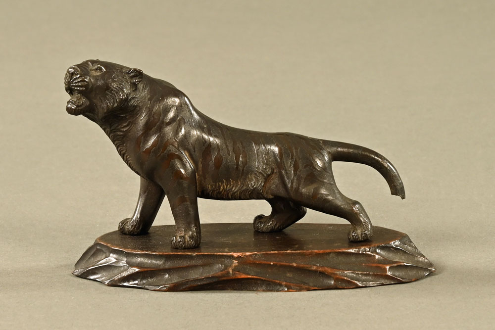 A Japanese bronze tiger, raised on a wooden plinth. Length 14 cm.