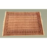 An Indian Bokhara silky pile fringed rug, with centre rectangular panel and multiple line border,