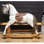 A dapple grey painted rocking horse, with leather bridle and saddle,